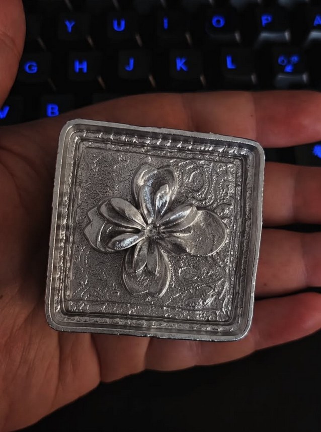 Cast plaque with floral relief, held in hand